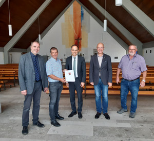 Staatssekretär Denis Alt übergibt Bescheid an Vertreter der Pfarrgemeinde Dümpelfeld in der Pfarrkirche.